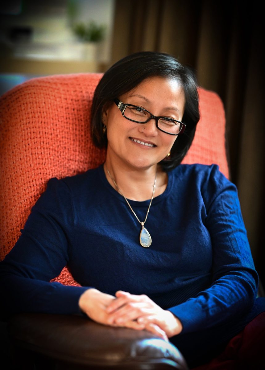 Van Seng smiling, seated in a coral armchair